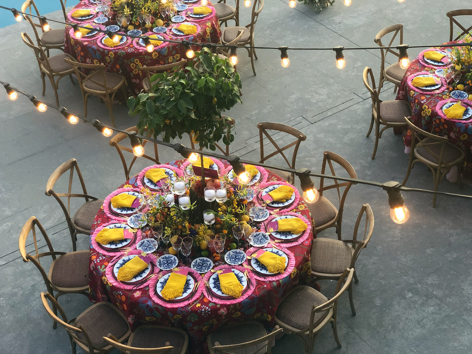 Top view of a round imperial table illuminated by a string of hanging light bulbs. - ACCAELLE Events | Organizzazione eventi e Wedding planner