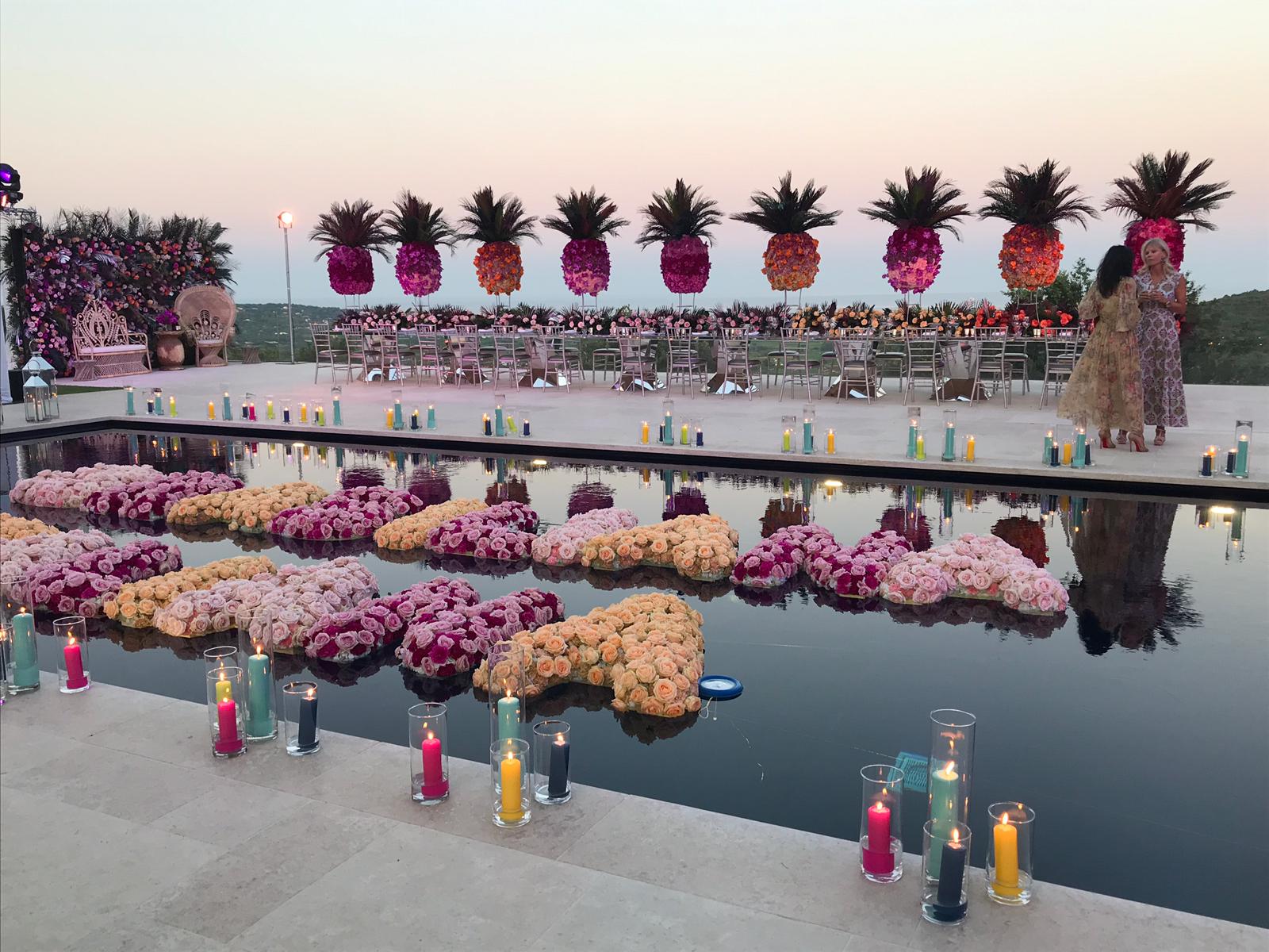 Scritta composta da fiori in piscina, ananas a fare da scenografia - ACCAELLE Events | Organizzazione eventi e Wedding planner