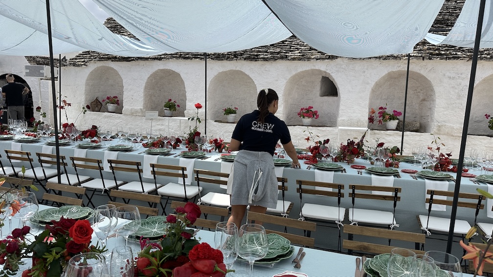 Ultimi preparativi di tavolata con fiori rossi e tovagliato bianco - ACCAELLE Events | Organizzazione eventi e Wedding planner
