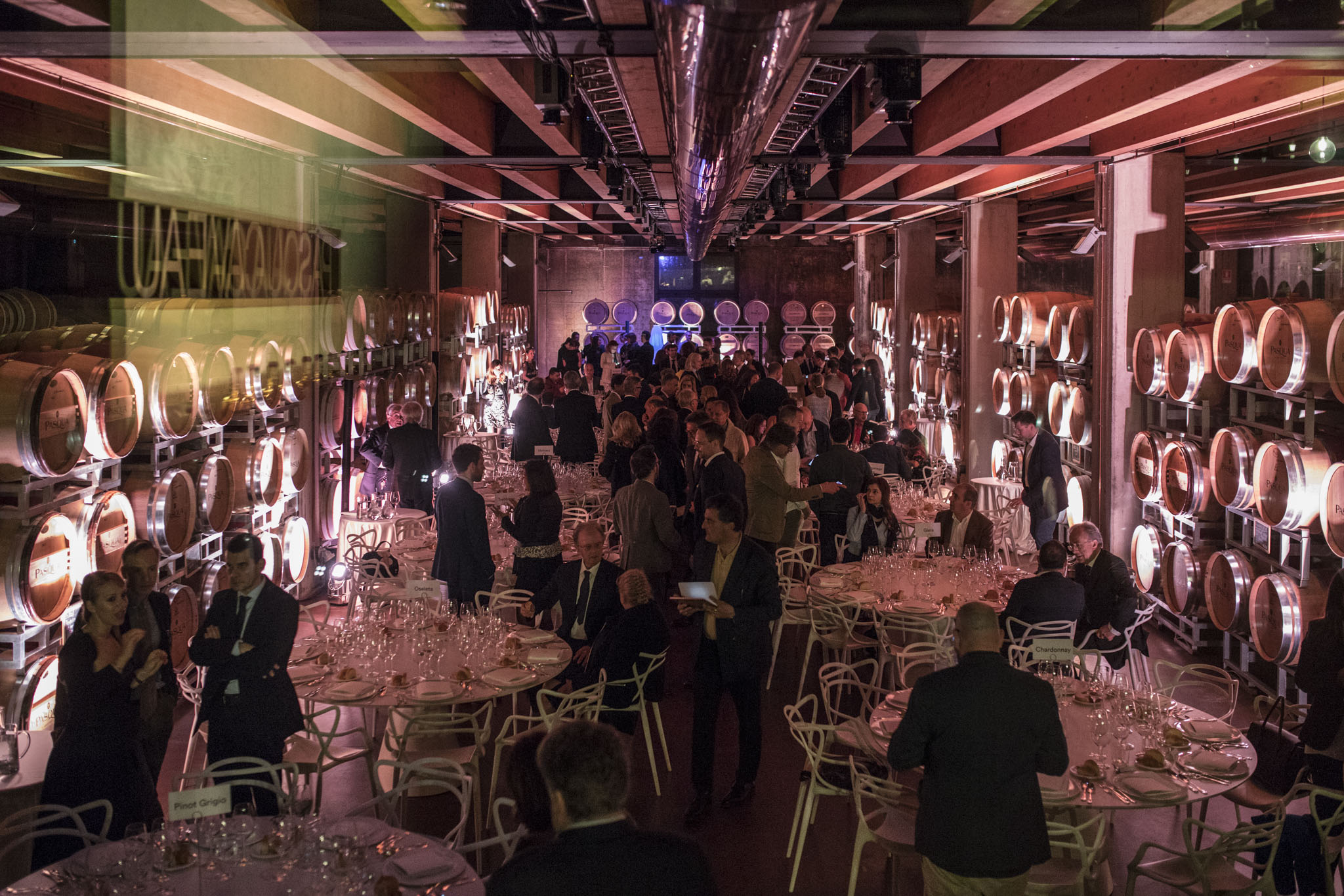  Ampia panoramica di un evento di gala con tavoli rotondi in una grande cantina. - ACCAELLE Events | Organizzazione eventi e Wedding planner
