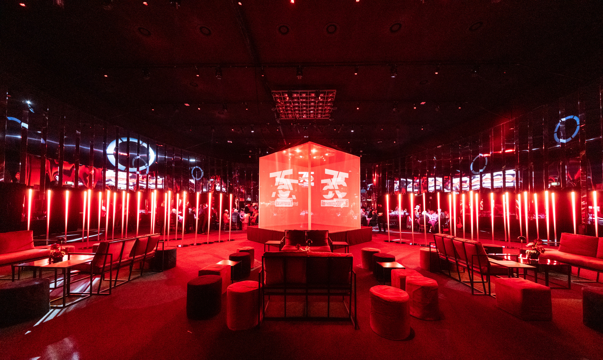 Ampia sala eventi allestita e illuminata con una scenografia geometrica rossa. - ACCAELLE Events | Organizzazione eventi e Wedding planner