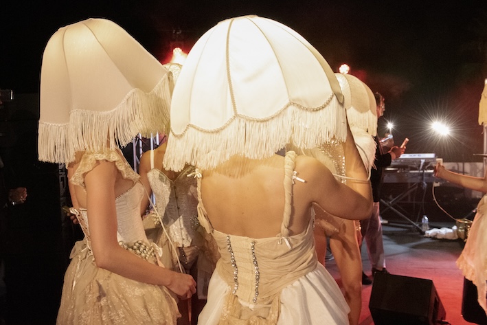Artisti in abiti vintage con grandi paralumi bianchi sulla testa durante uno spettacolo serale - ACCAELLE Events | Organizzazione eventi e Wedding planner