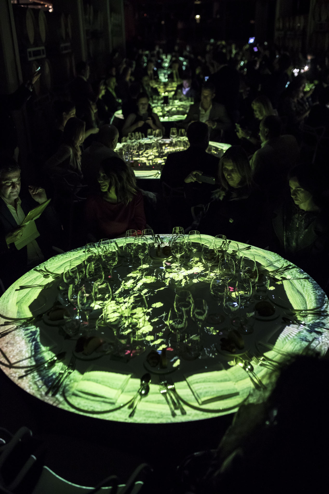 Cena di gala con tavoli illuminati da proiezioni grafiche verdi animate al buio. - ACCAELLE Events | Organizzazione eventi e Wedding planner