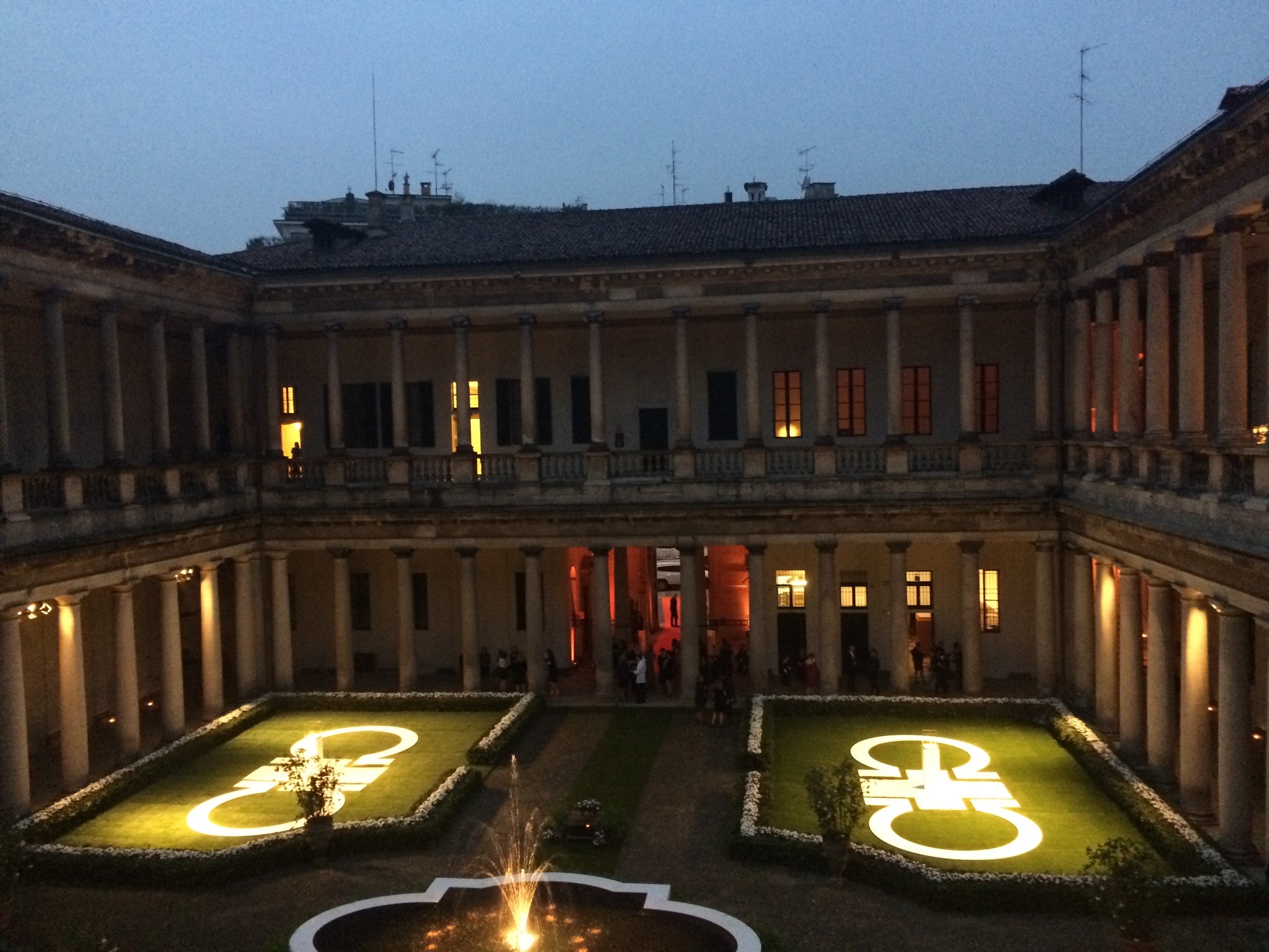 Cortile monumentale illuminato di sera con proiezioni di loghi luminosi sul prato. - ACCAELLE Events | Organizzazione eventi e Wedding planner