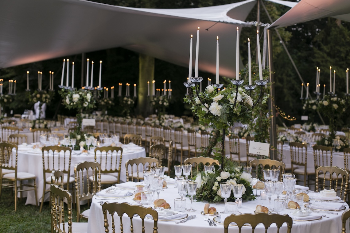 Dettaglio dei tavoli per cena matrimoniale con decorazioni floreali e grossi candelabri al centro - ACCAELLE Events | Organizzazione eventi e Wedding planner