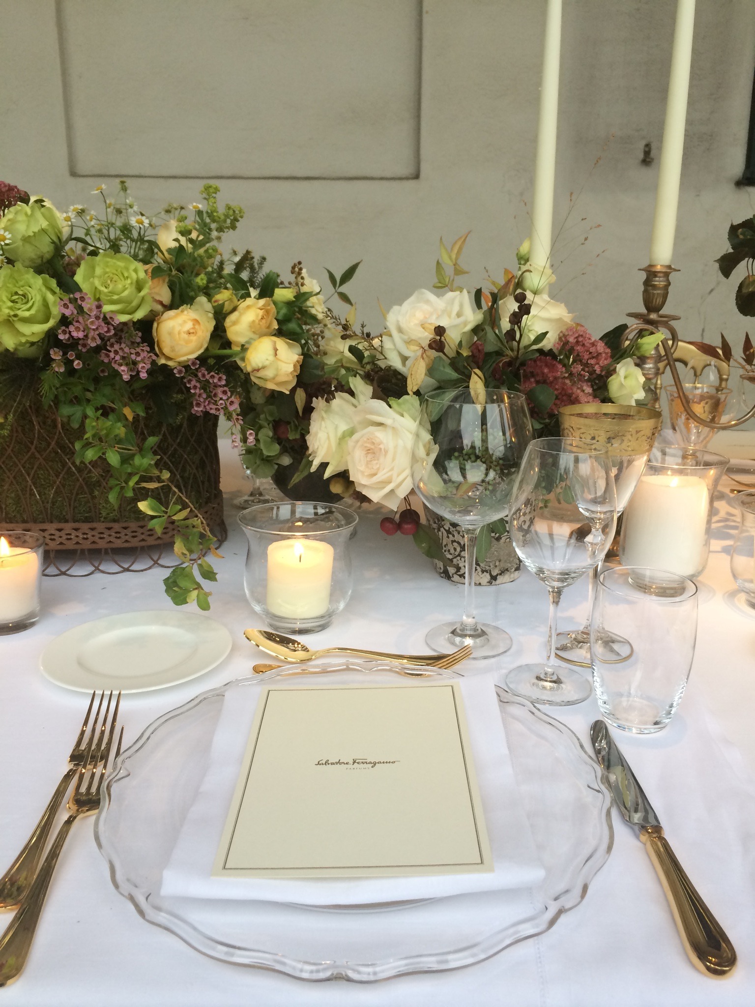 Dettaglio della mise en place elegante con piatti bianchi, posate dorate, fiori e candele. - ACCAELLE Events | Organizzazione eventi e Wedding planner