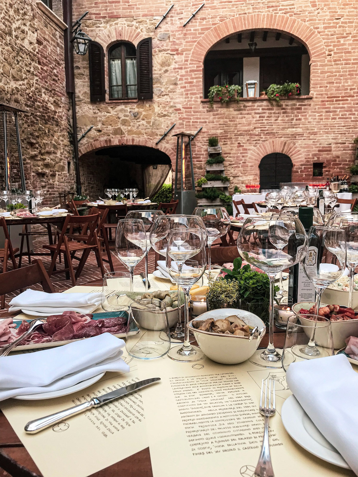 Dettaglio della mise en place rustica con piatti e posate nel cortile in mattoni del castello - ACCAELLE Events | Organizzazione eventi e Wedding planner