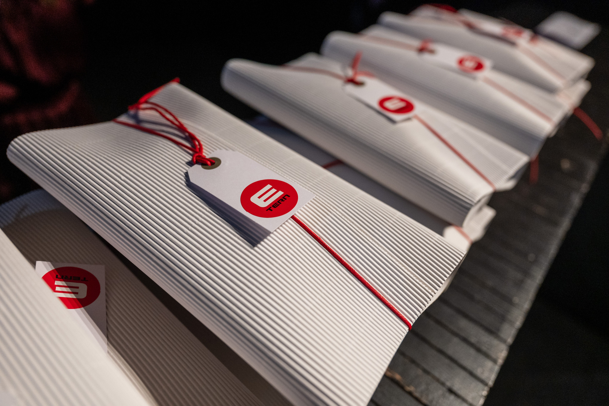 Fila di gadget bianchi personalizzati con cordino rosso ed etichetta. - ACCAELLE Events | Organizzazione eventi e Wedding planner