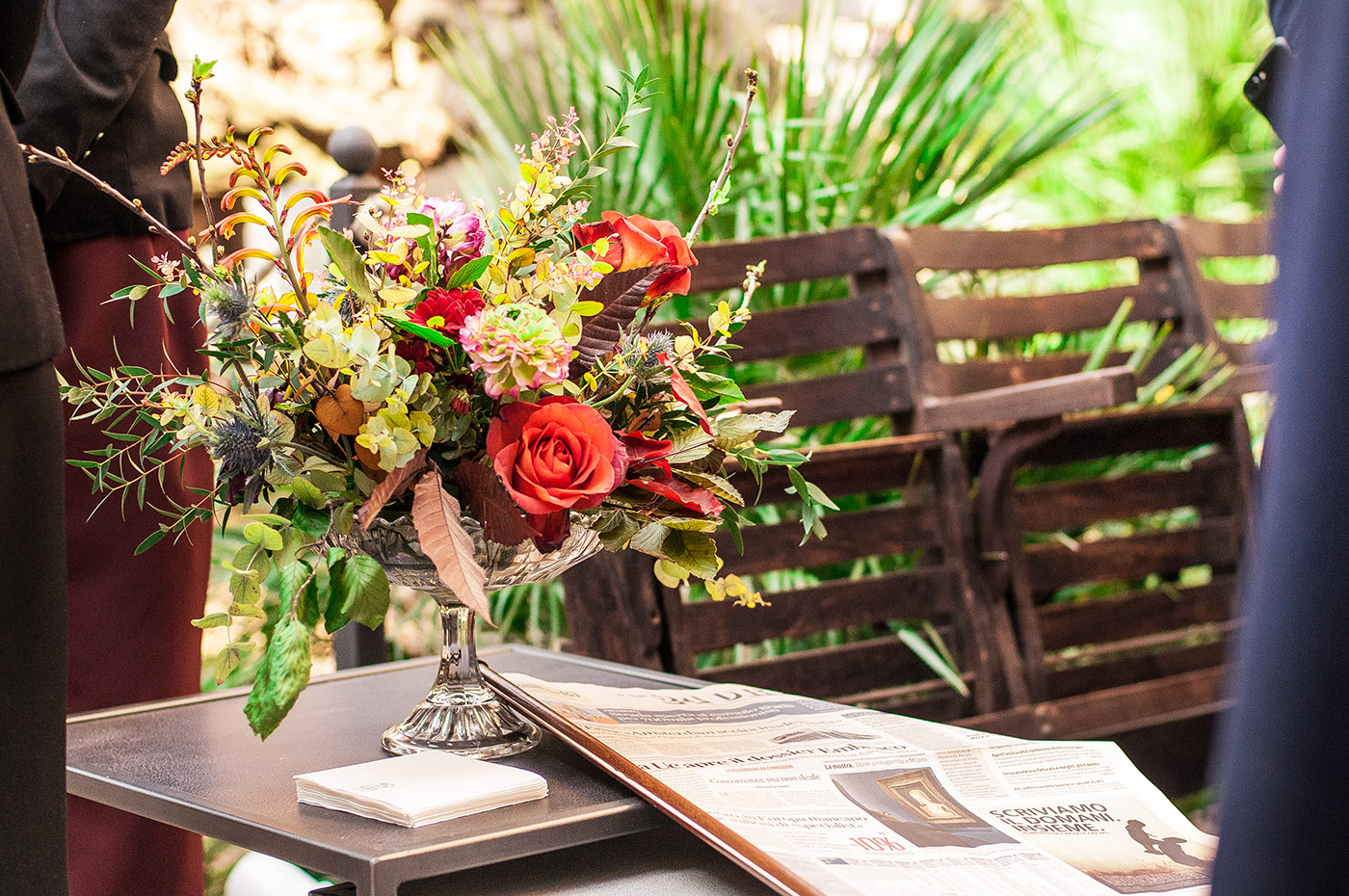 Giornali stampati posati su un tavolo di legno decorato con fiori colorati - ACCAELLE Events | Organizzazione eventi e Wedding planner