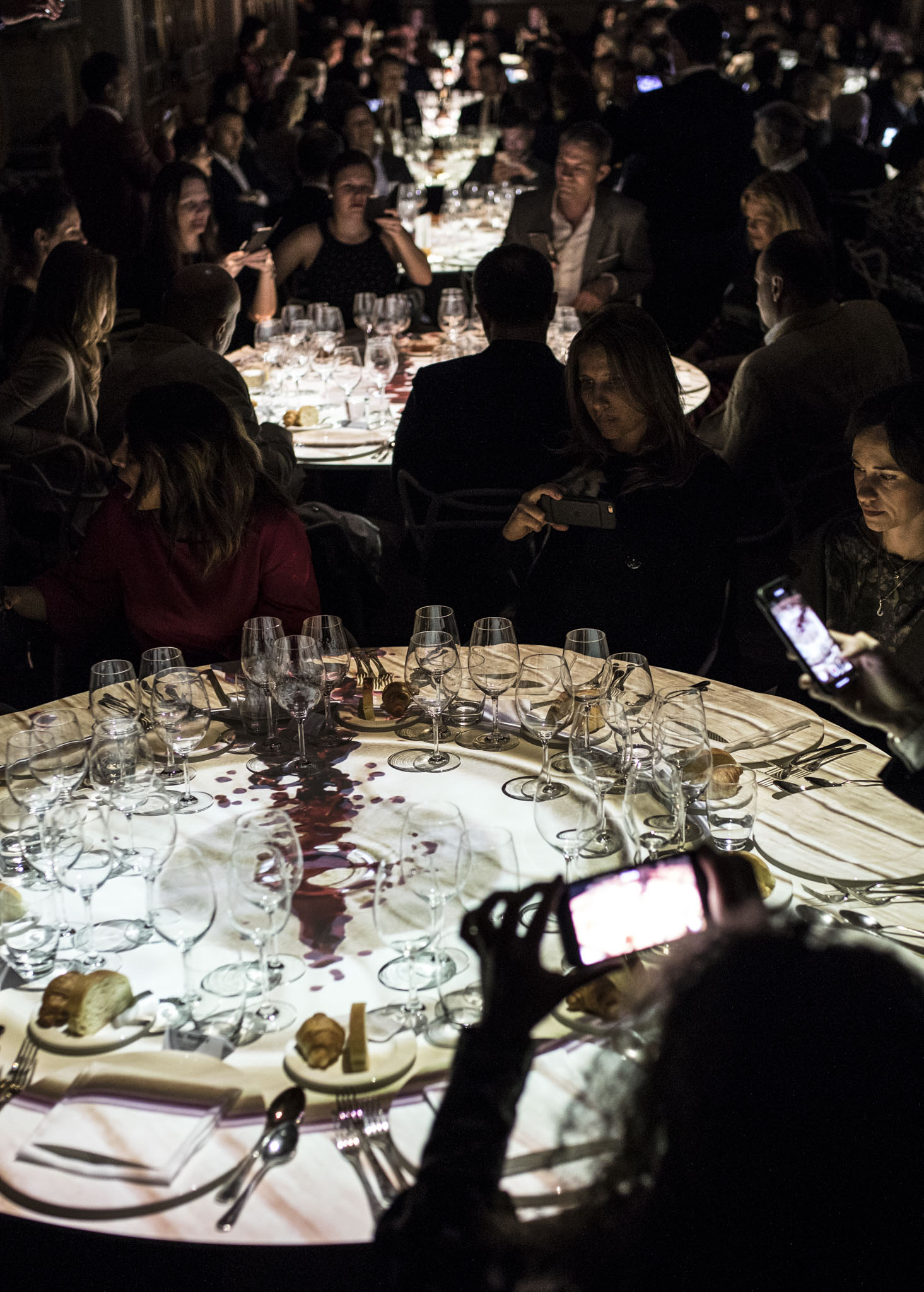Invitati che fotografano con lo smartphone un tavolo illuminato da video mapping. - ACCAELLE Events | Organizzazione eventi e Wedding planner