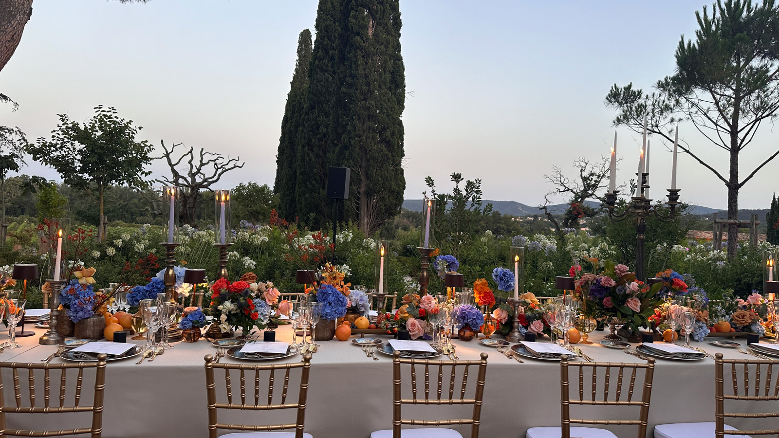 Panoramica di una lunga tavolata in campagna circondata da alberi e cipressi. - ACCAELLE Events | Organizzazione eventi e Wedding planner