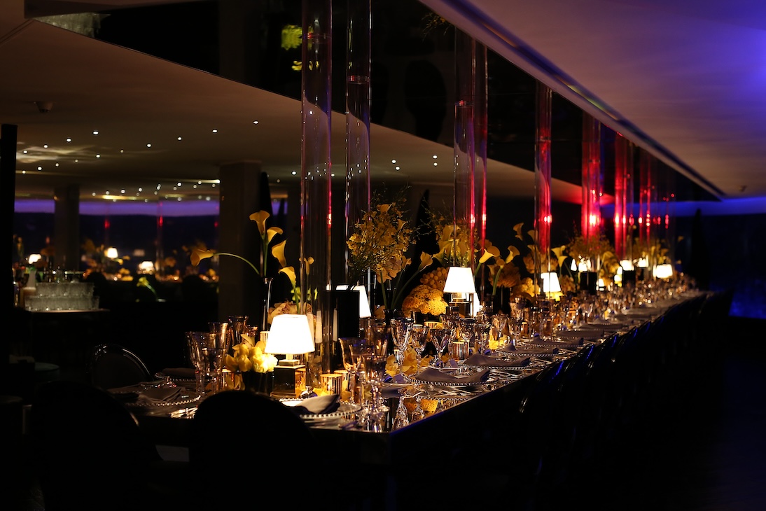 Panoramica di una sala eventi con lunga tavolata apparecchiata e luci d'atmosfera - ACCAELLE Events | Organizzazione eventi e Wedding planner