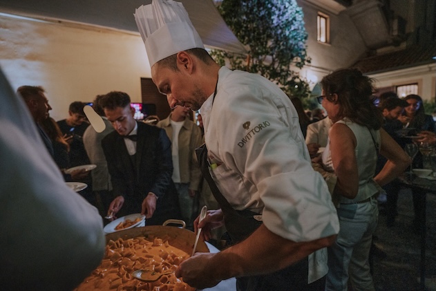 Primo piano commensale che serve della pasta agli ospiti durante un banchetto serale - ACCAELLE Events | Organizzazione eventi e Wedding planner