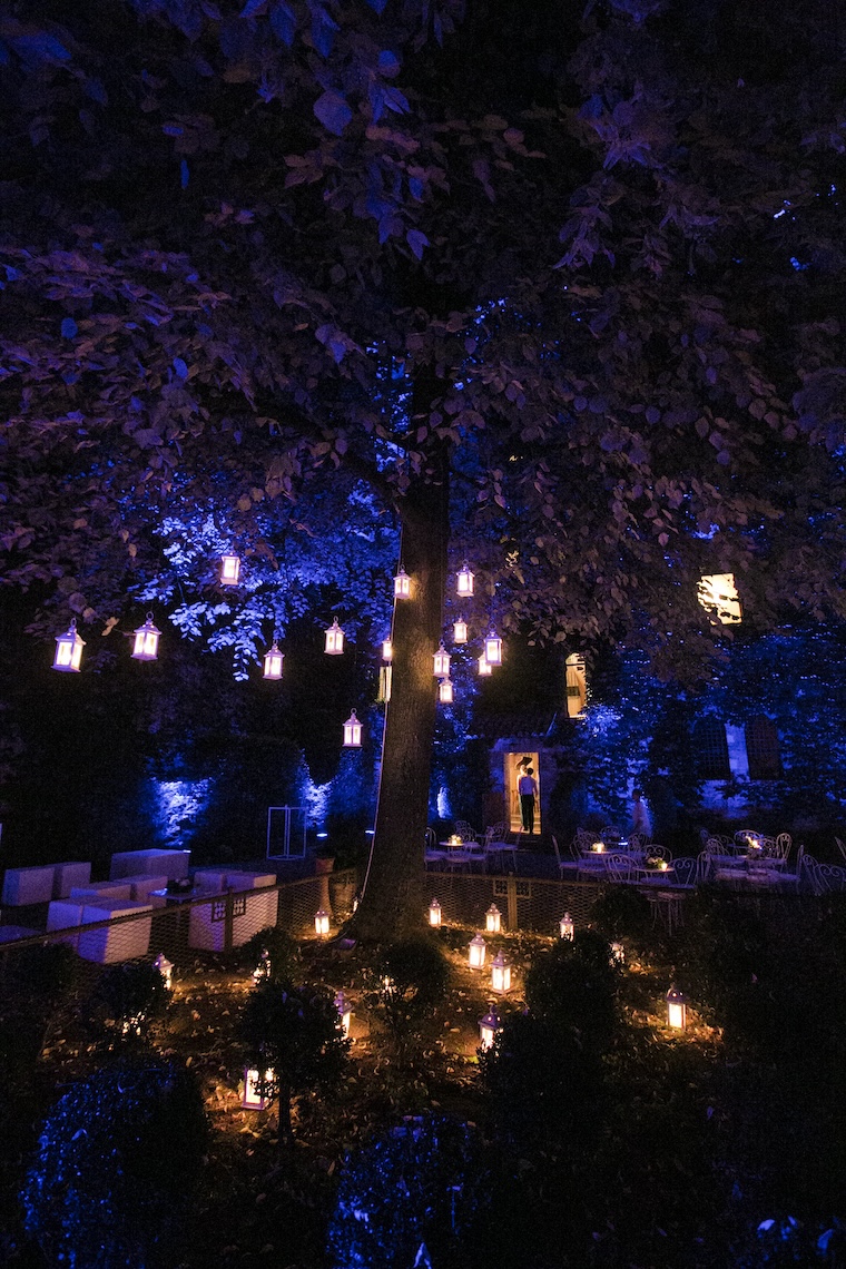 Primo piano di un albero di sera illuminato da luci blu e lanterne appese ai rami - ACCAELLE Events | Organizzazione eventi e Wedding planner