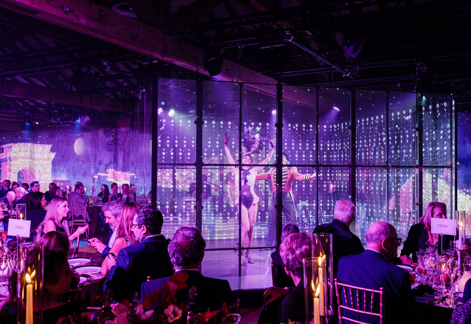 Sala ricevimenti affollata con due artisti che ballano dentro una gabbia illuminata. - ACCAELLE Events | Organizzazione eventi e Wedding planner
