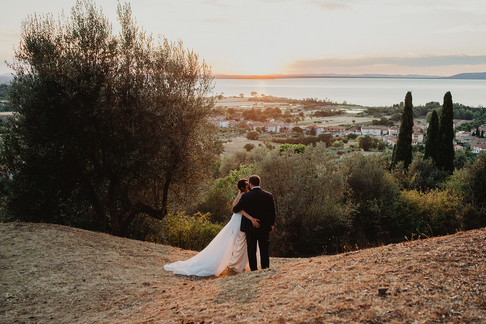 Sposi che posano guardando il tramonto in un paesaggio marittimo  - ACCAELLE Events | Organizzazione eventi e Wedding planner