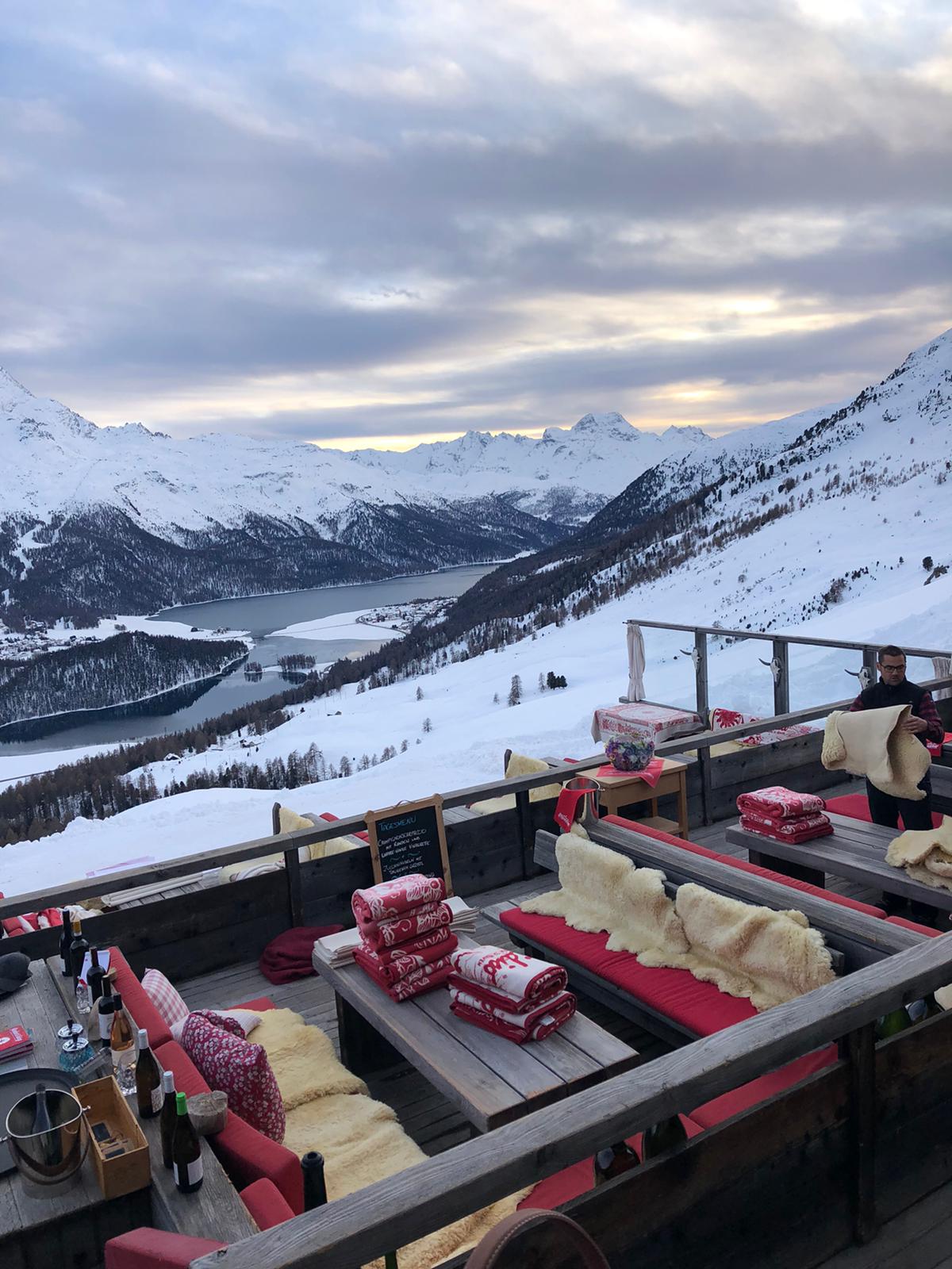 Terrazza panoramica allestita per un evento esclusivo in montagna, con sedute, coperte e montagne innevate sullo sfondo - ACCAELLE Events | Organizzazione eventi e Wedding planner