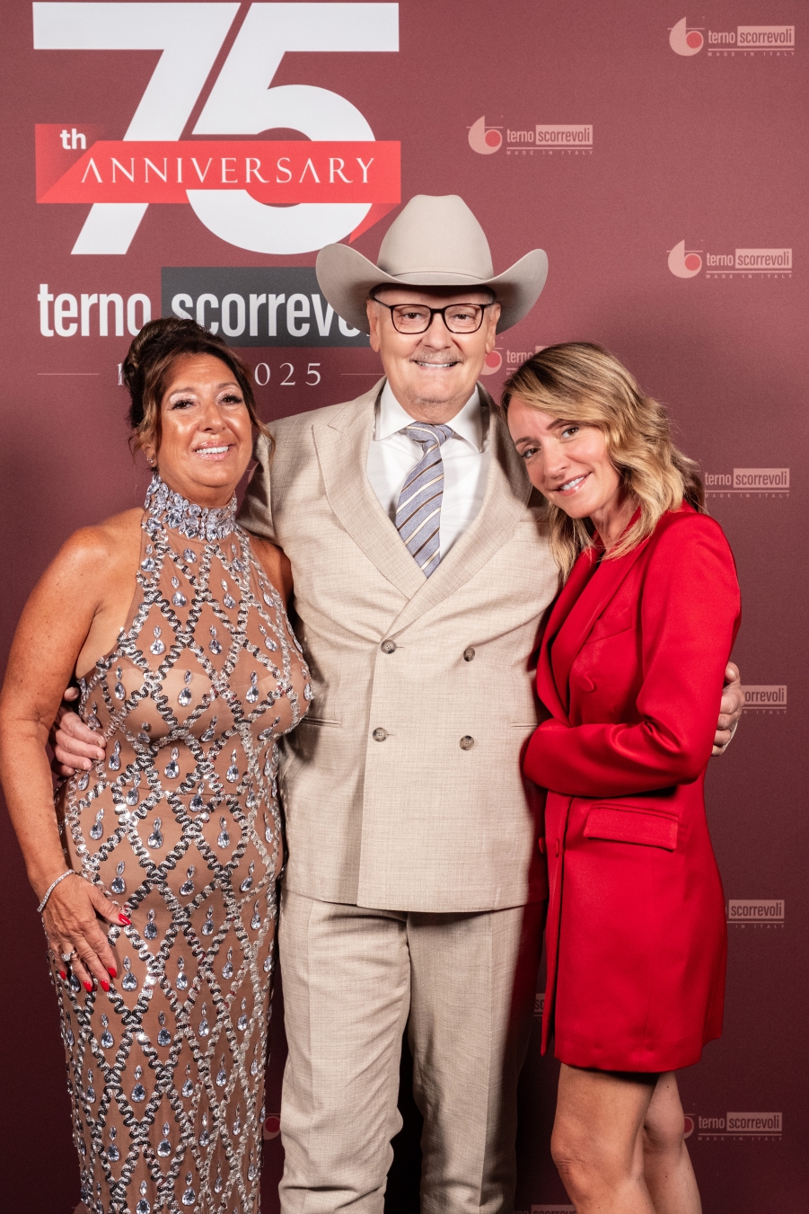 Tre persone che posano sorridenti davanti ad un cartellone per un 75° anniversario  - ACCAELLE Events | Organizzazione eventi e Wedding planner