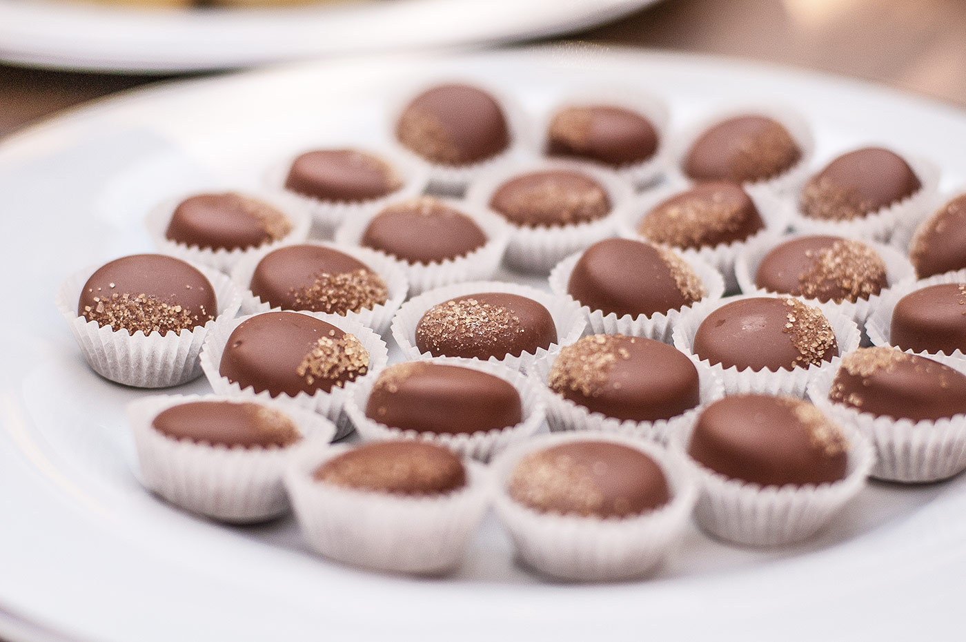 Vassoio circolare pieno di piccoli pasticcini al cioccolato disposti con ordine. - ACCAELLE Events | Organizzazione eventi e Wedding planner